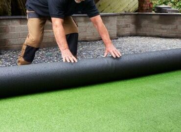 artificial grass being unrolled for turf instalation in residential property